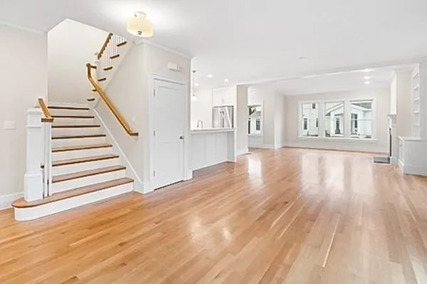 a view of an empty room with wooden floor and stairs