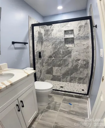 a bathroom with a granite countertop sink toilet and shower