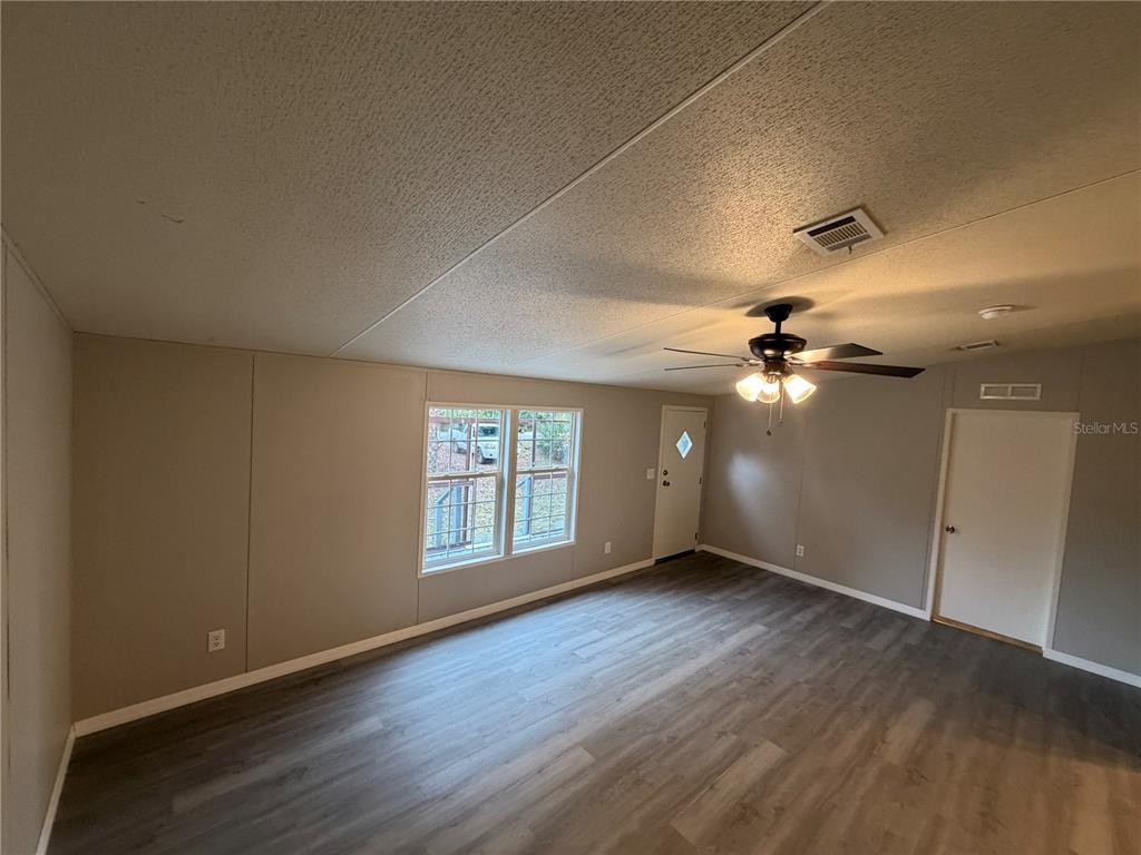 212 Paradise Shores Road Crescent City, FL 32112 - Photo 8 of 23 an empty room with wooden floor fan and windows