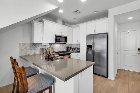 a kitchen with stainless steel appliances granite countertop a refrigerator a stove a sink a dining table and chairs