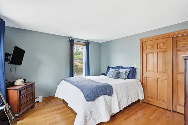 a bedroom with a bed and flat tv screen on the dresser