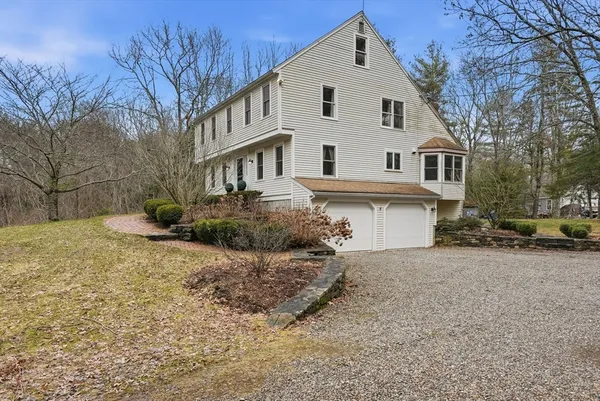 a view of a white house next to a road and yard