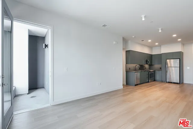 a view of kitchen with stainless steel appliances kitchen island wooden floor and living room