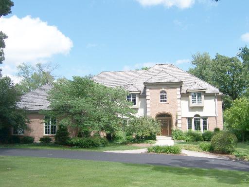 a view of a white house next to a yard with big trees