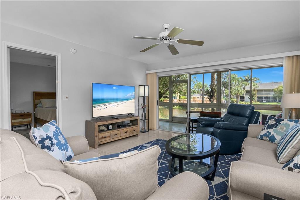 1330 Yesica Ann Circle, Unit I106 Naples, FL 34110 - Photo 2 of 38 a living room with furniture a flat screen tv and a large window