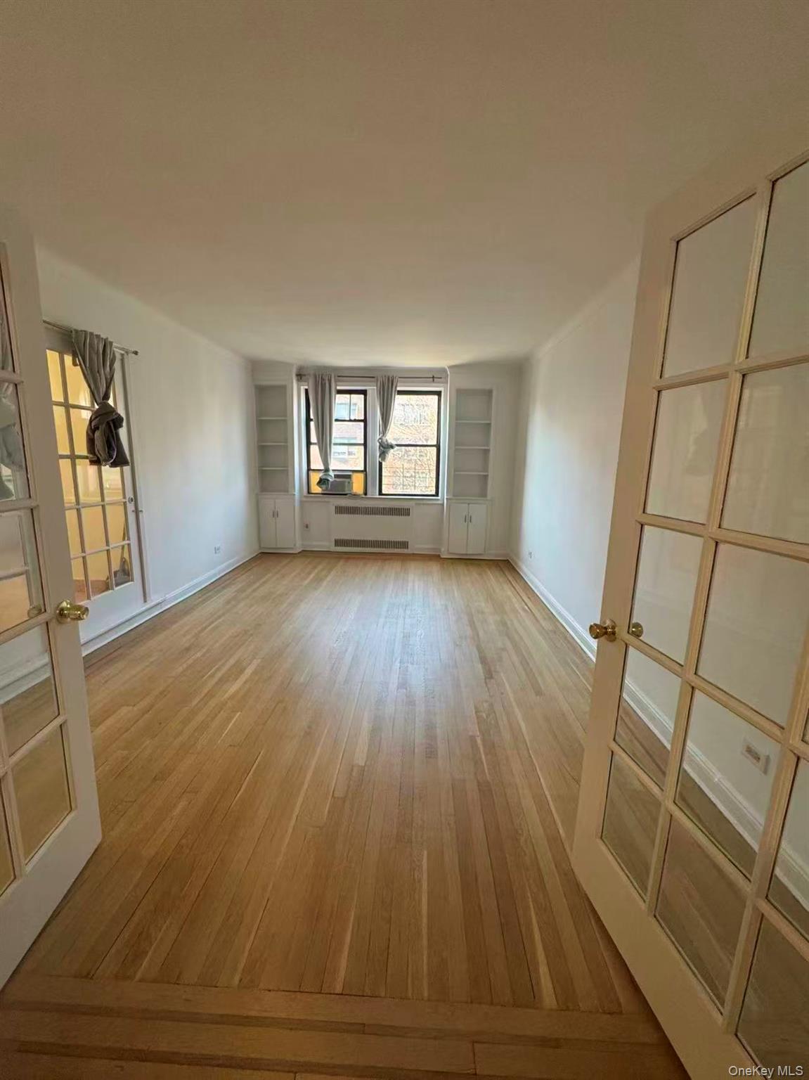 99-34 67th Road, Unit 5D Queens, NY 11375 - Photo 5 of 6 wooden floor in an empty room with a window