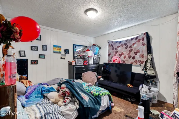 a bedroom with a bed and dresser with the shoe rack