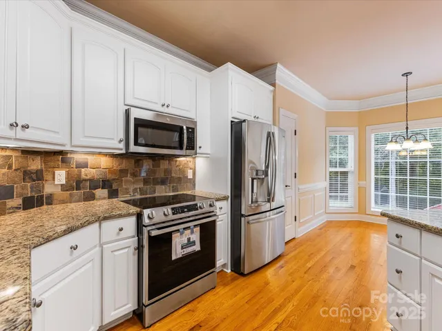 a kitchen with granite countertop a refrigerator stove and microwave