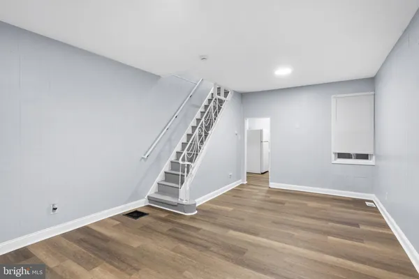 a view of an empty room with wooden floor and stairs
