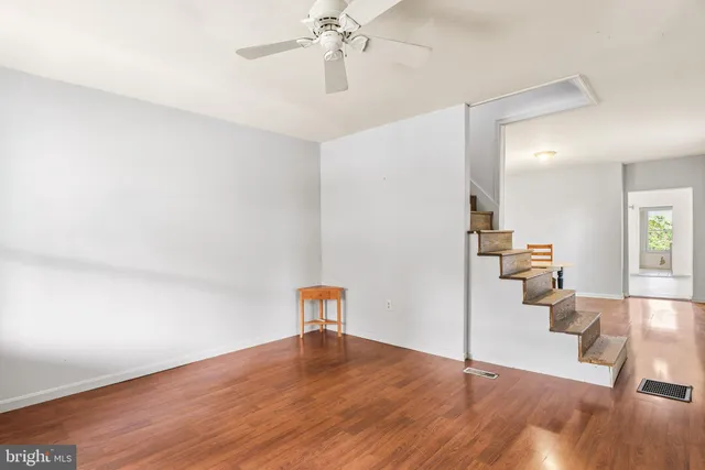 a view of an empty room with a window and wooden floor