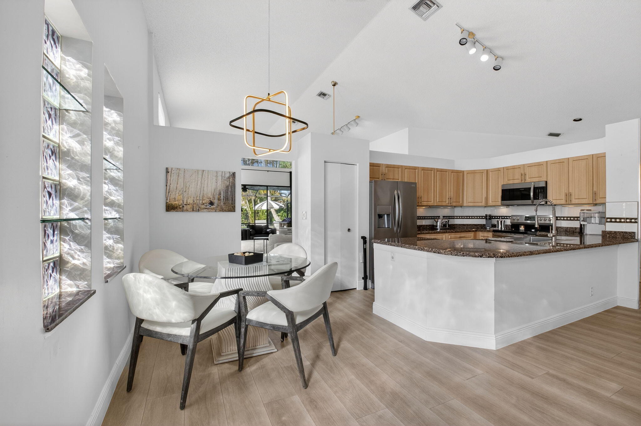 9060 Villa Portofino Circle Boca Raton, FL 33496 - Photo 17 of 47 a kitchen with stainless steel appliances kitchen island granite countertop a table chairs and a refrigerator