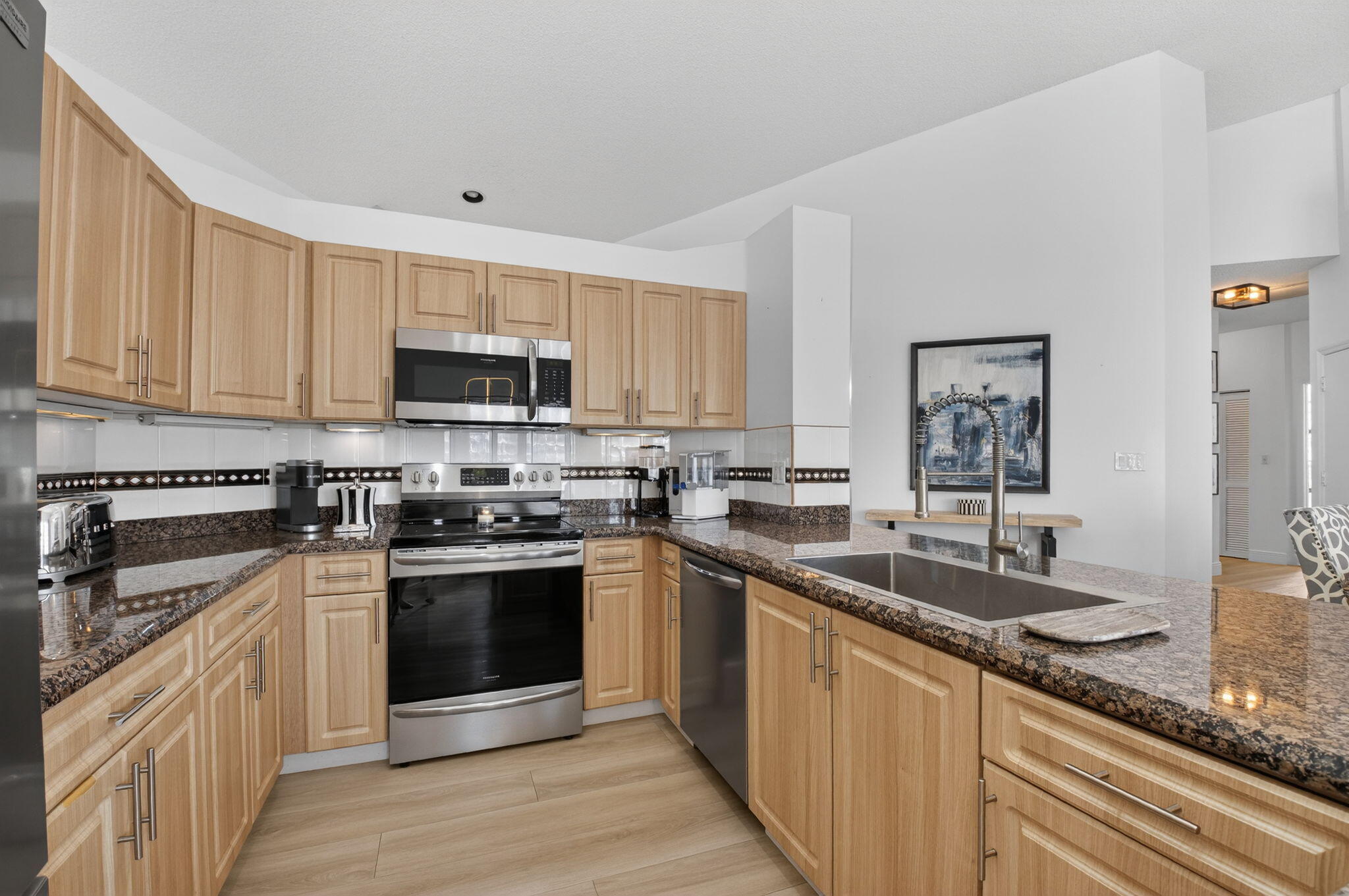 9060 Villa Portofino Circle Boca Raton, FL 33496 - Photo 21 of 47 a kitchen with stainless steel appliances granite countertop a stove top oven a sink and dishwasher a refrigerator with wooden cabinets