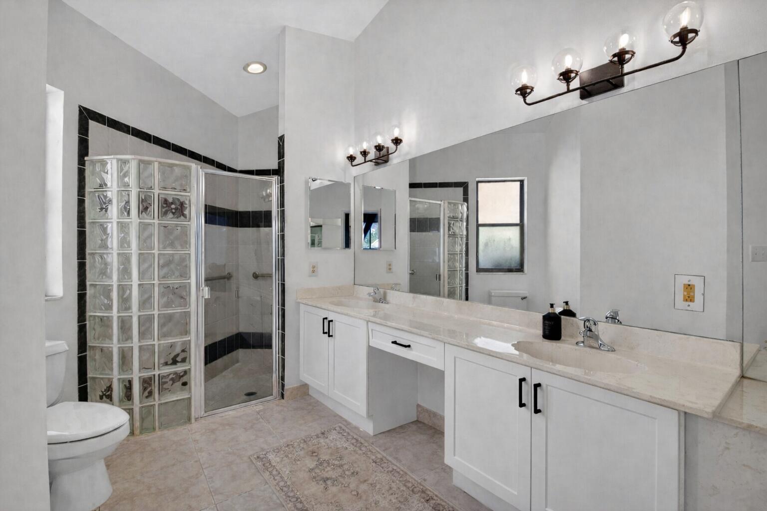 9060 Villa Portofino Circle Boca Raton, FL 33496 - Photo 27 of 47 a spacious bathroom with a double vanity sink toilet and shower