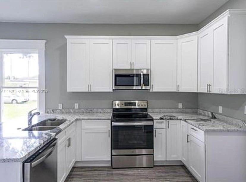 475 Sunset Road North Rotonda West, FL 33947 - Photo 3 of 14 a kitchen with granite countertop white cabinets and white appliances