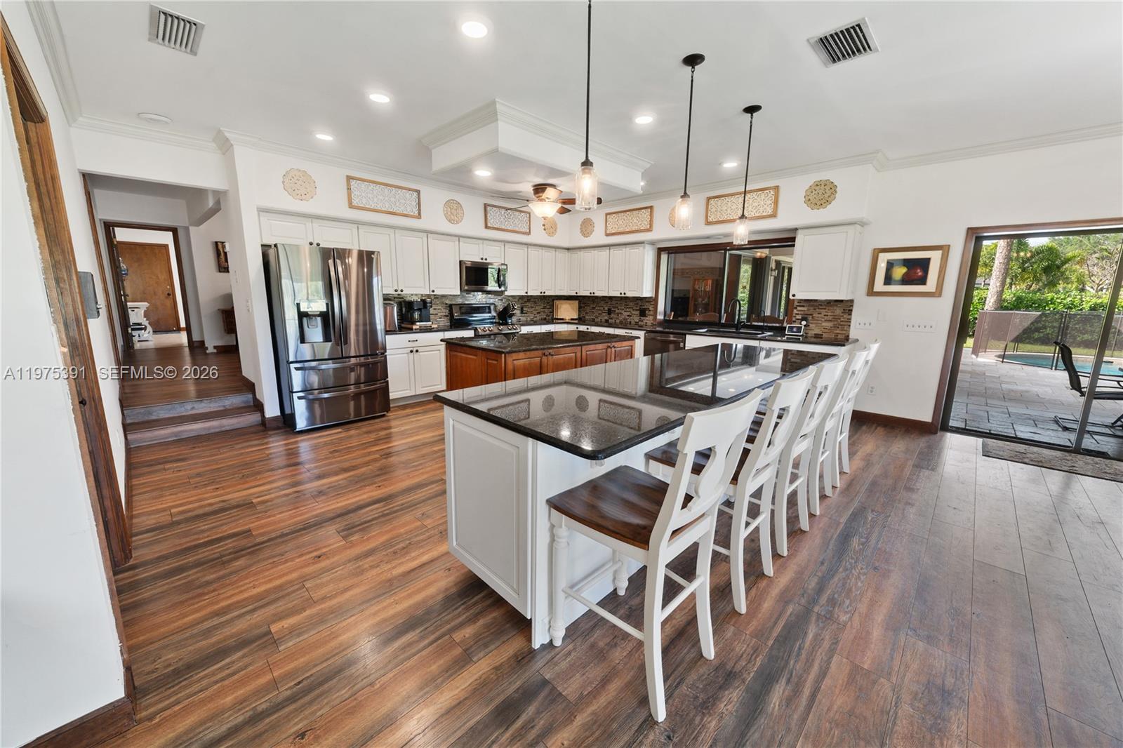 1872 Southeast Colony Way Jupiter, FL 33478 - Photo 24 of 26 a kitchen with stainless steel appliances kitchen island granite countertop a table chairs and a refrigerator