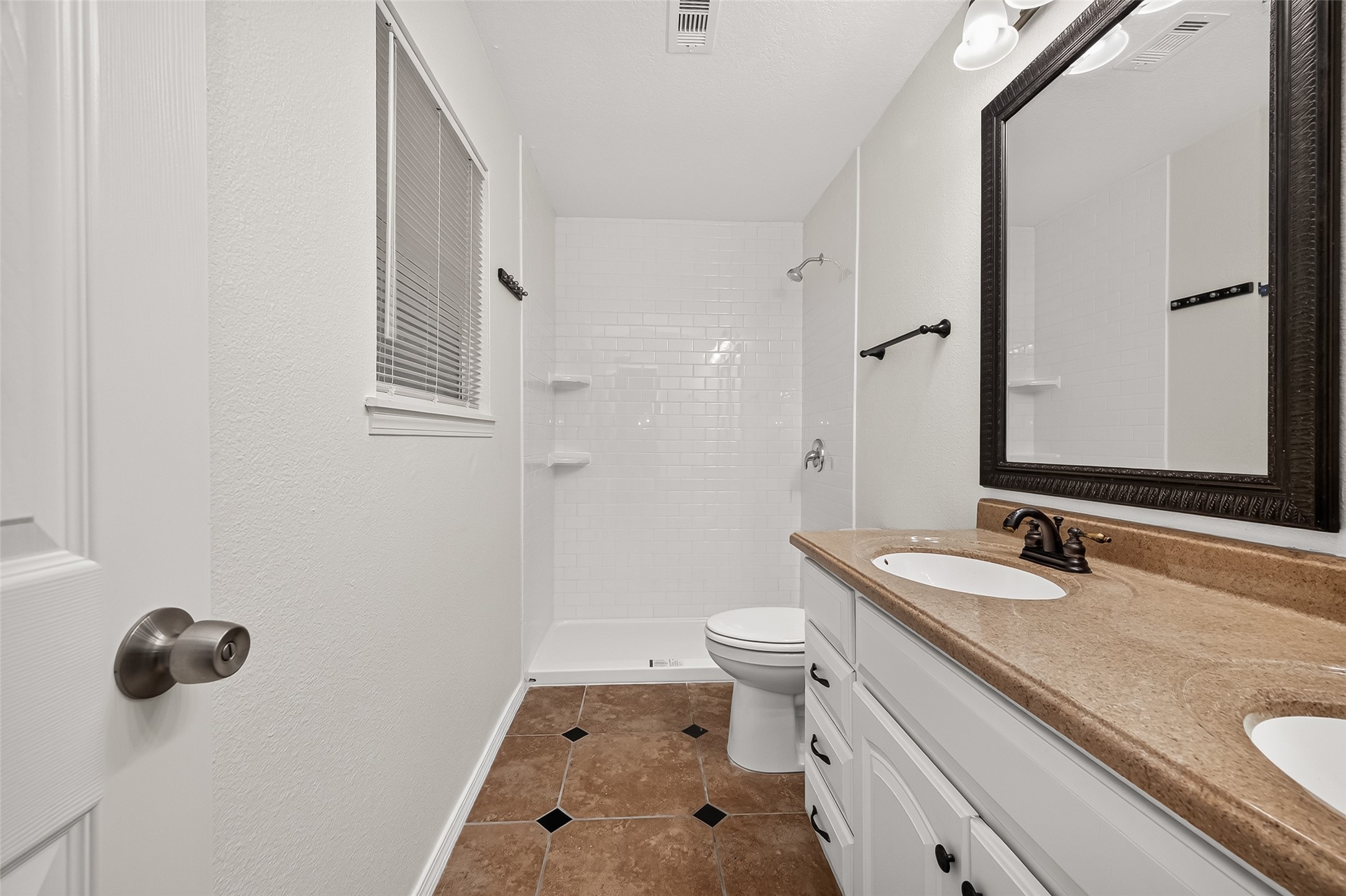 9322 Magnolia Ridge Drive Houston, TX 77070 - Photo 13 of 16 Primary bathroom featuring double vanity, fresh paint, new window blinds, and a brand new walk-in shower with white subway tile.