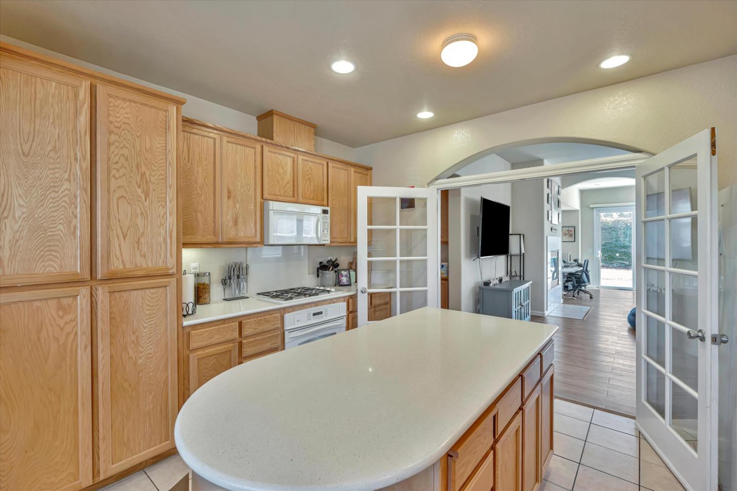 390 Munter Street Manteca, CA 95337 - Photo 7 of 26 a kitchen with kitchen island a stove a sink a refrigerator and white cabinets with wooden floor
