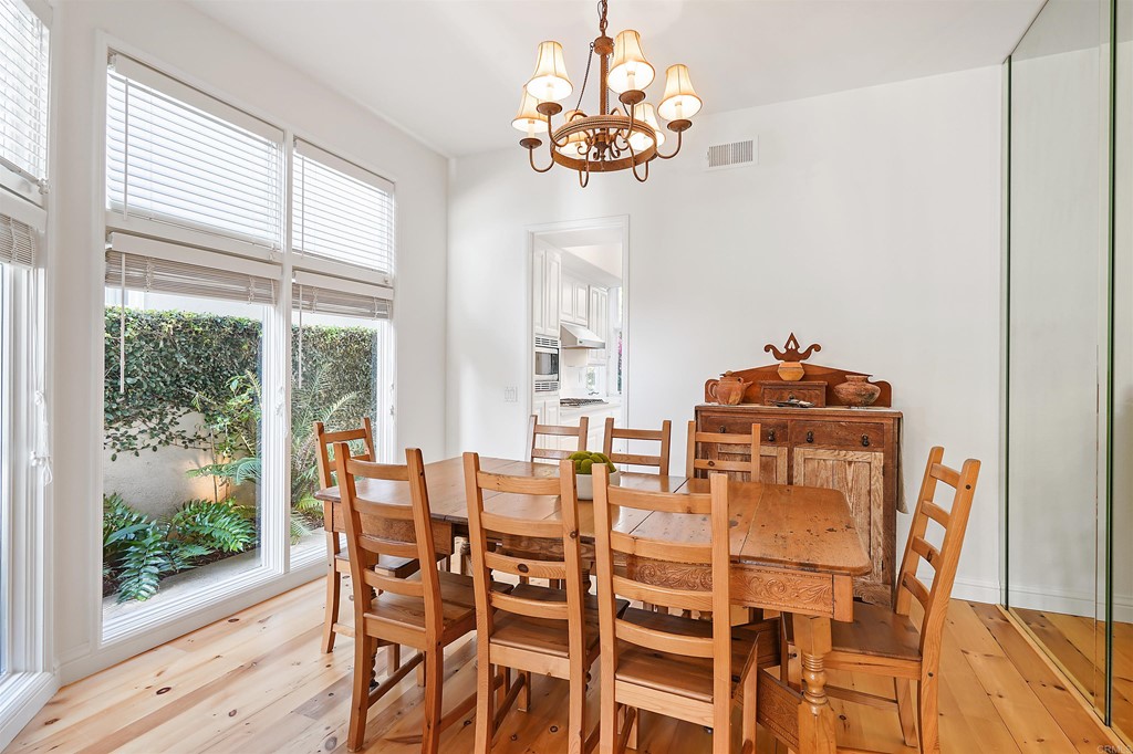 9735 Claiborne Square La Jolla, CA 92037 - Photo 15 of 60 a dining room with furniture a chandelier and wooden floor