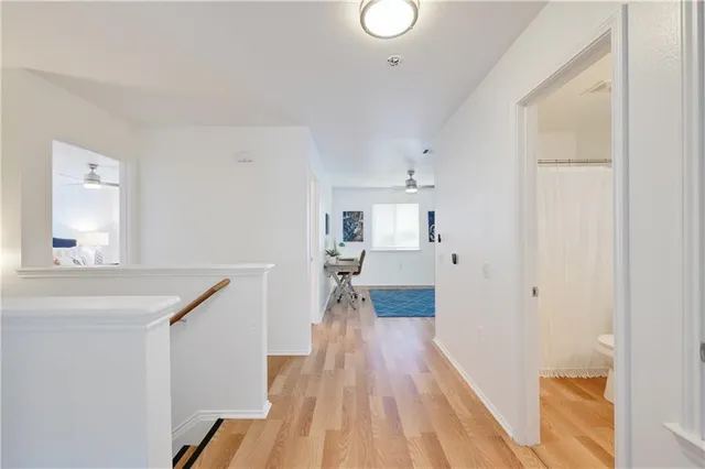 a view of a hallway with wooden floor and a bathroom