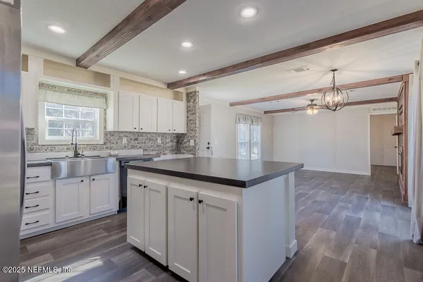 a kitchen with kitchen island granite countertop a sink cabinets and wooden floor