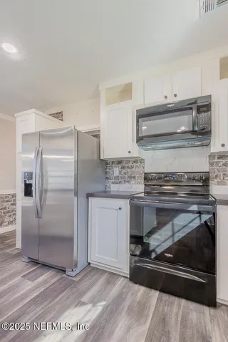 a kitchen with granite countertop a refrigerator and a stove top oven