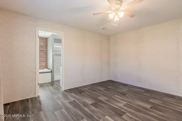 a view of empty room with wooden floor and fan