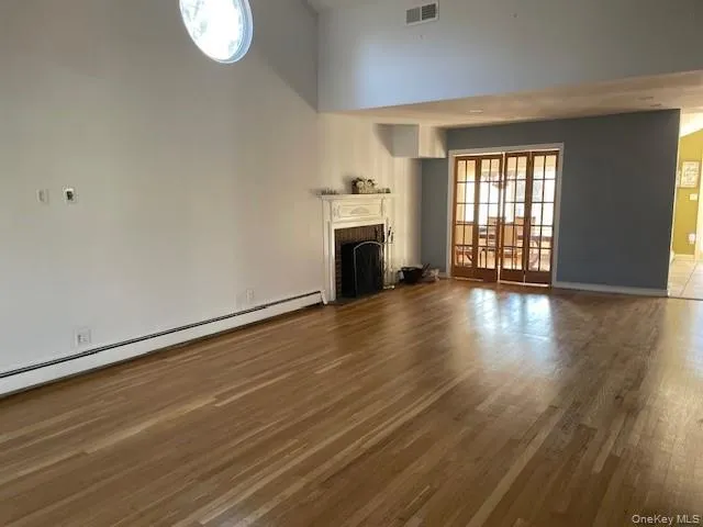 an empty room with wooden floor fireplace and windows