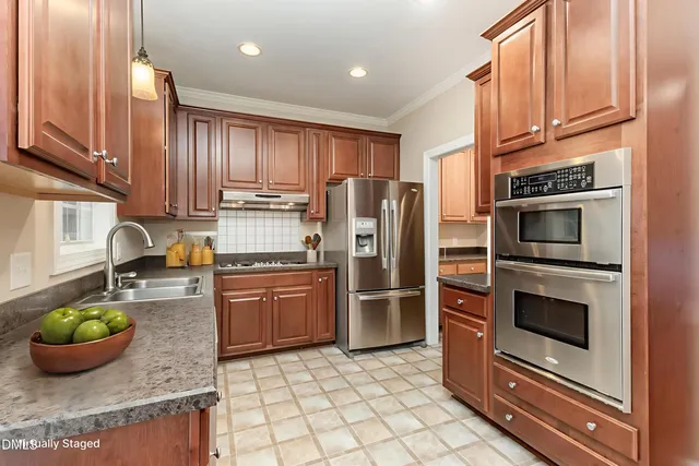 a kitchen with stainless steel appliances granite countertop wooden cabinets a sink and a stove
