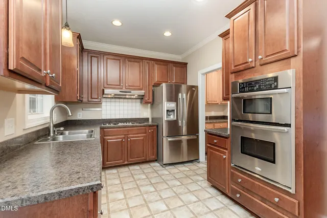 a kitchen with kitchen island granite countertop a refrigerator stove and sink