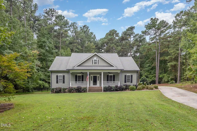 a front view of a house with a garden and trees