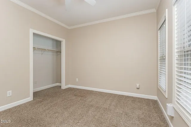 an empty room with closet and a ceiling fan
