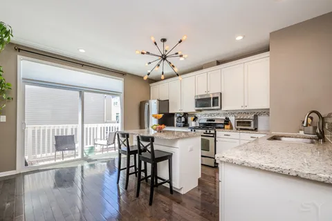 a kitchen with granite countertop a stove a sink a dining table and chairs