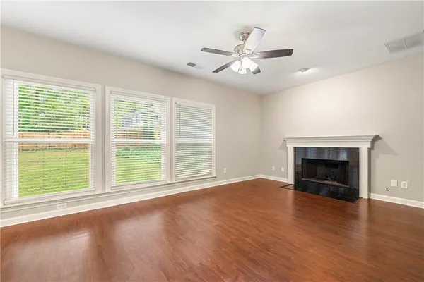 a view of an empty room with wooden floor fireplace and a window