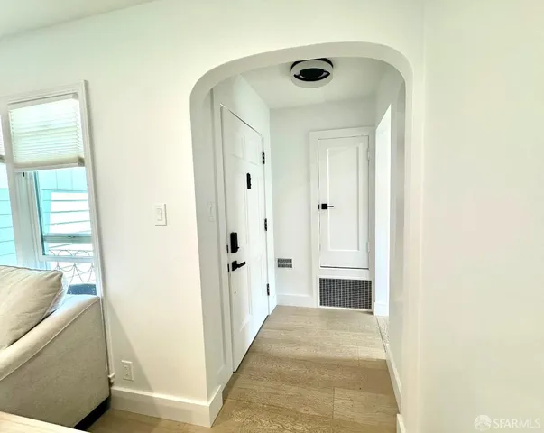 a view of a hallway with wooden floor and a living room