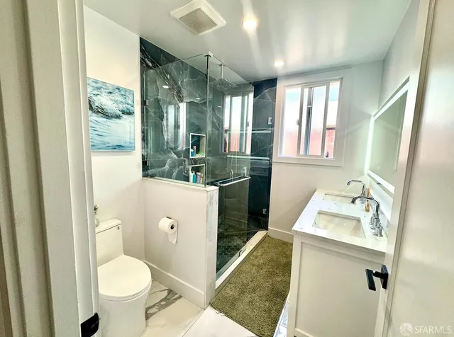 a bathroom with a sink a toilet and shower