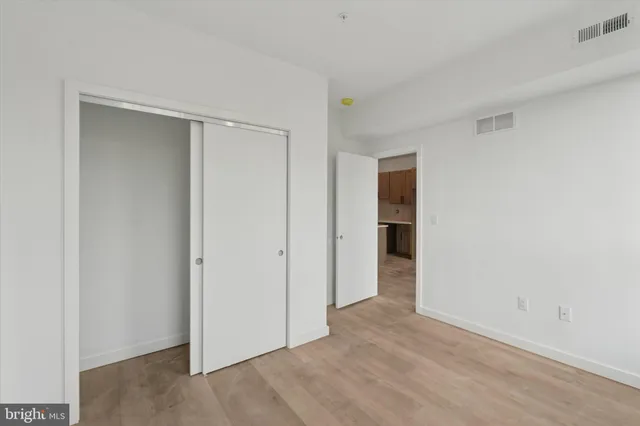 a view of an empty room with closet and wooden floor