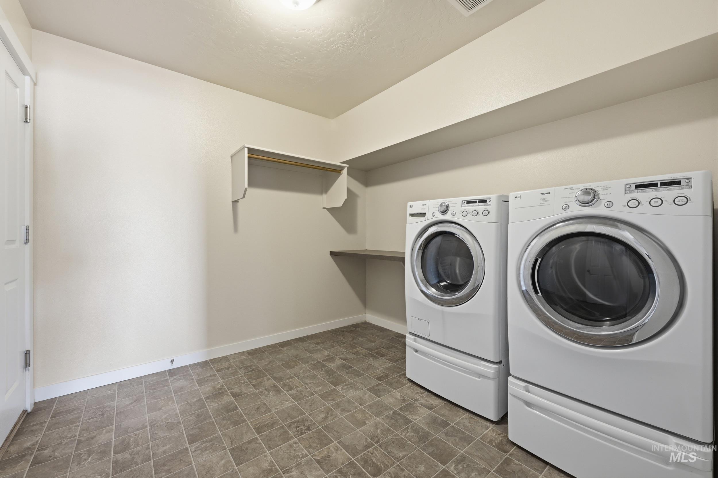 4855 South Chex Way Boise, ID 83709 - Photo 38 of 47 Dedicated laundry room featuring tile-finish flooring, included washer and dryer appliances, wall-mounted shelving with hanging rod, and a built-in counter surface