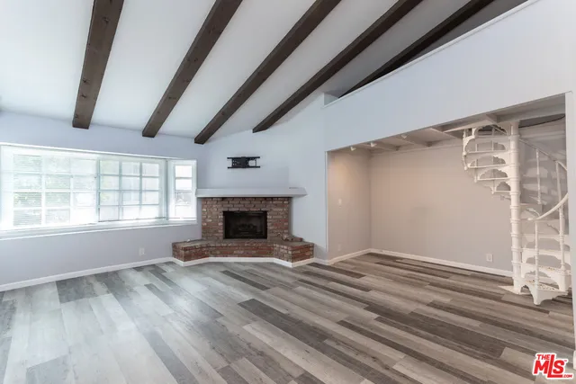 a view of empty room with wooden floor and fireplace