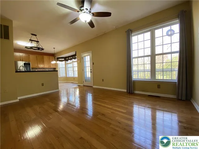 a view of an empty room with window and wooden floor