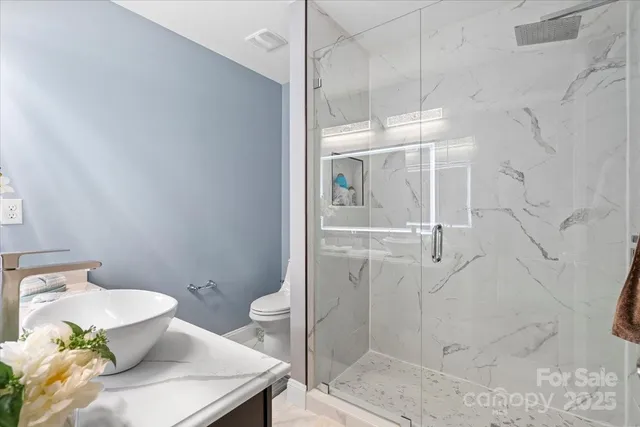 a bathroom with a granite countertop shower a sink and toilet