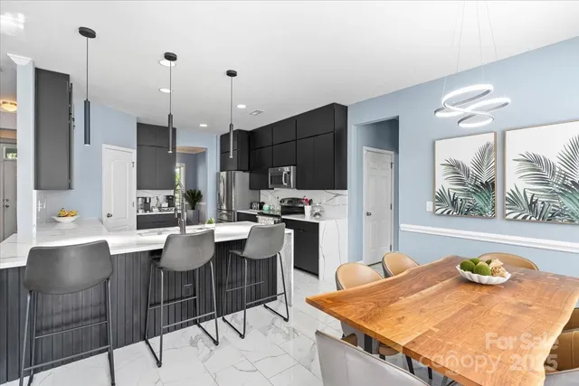 a living room with stainless steel appliances kitchen island granite countertop a table chairs and a refrigerator