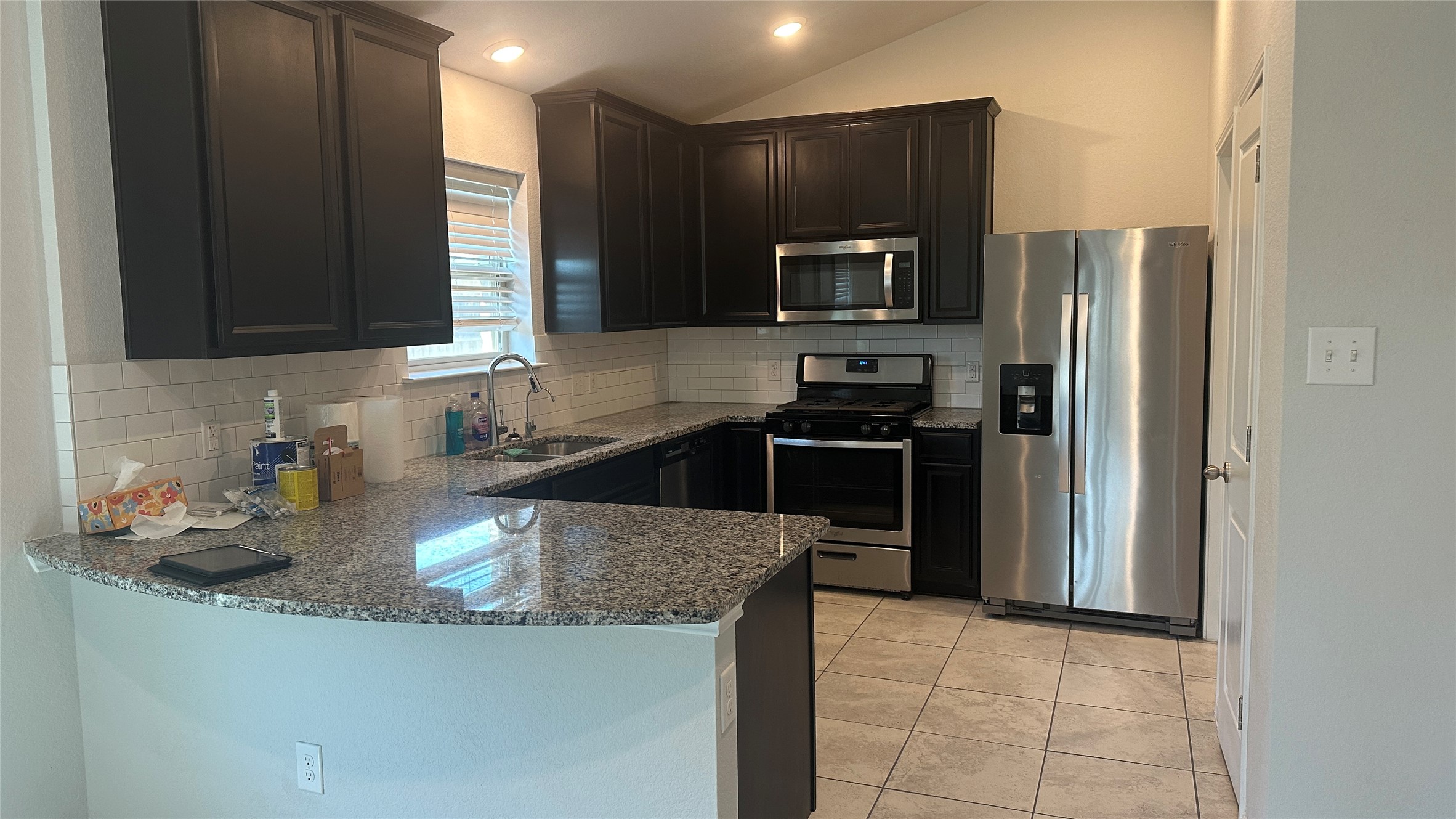 12321 Caldera Way Manor, TX 78653 - Photo 11 of 18 Kitchen featuring stainless steel appliances, dark stone countertops, light tile patterned floors, tasteful backsplash, and vaulted ceiling