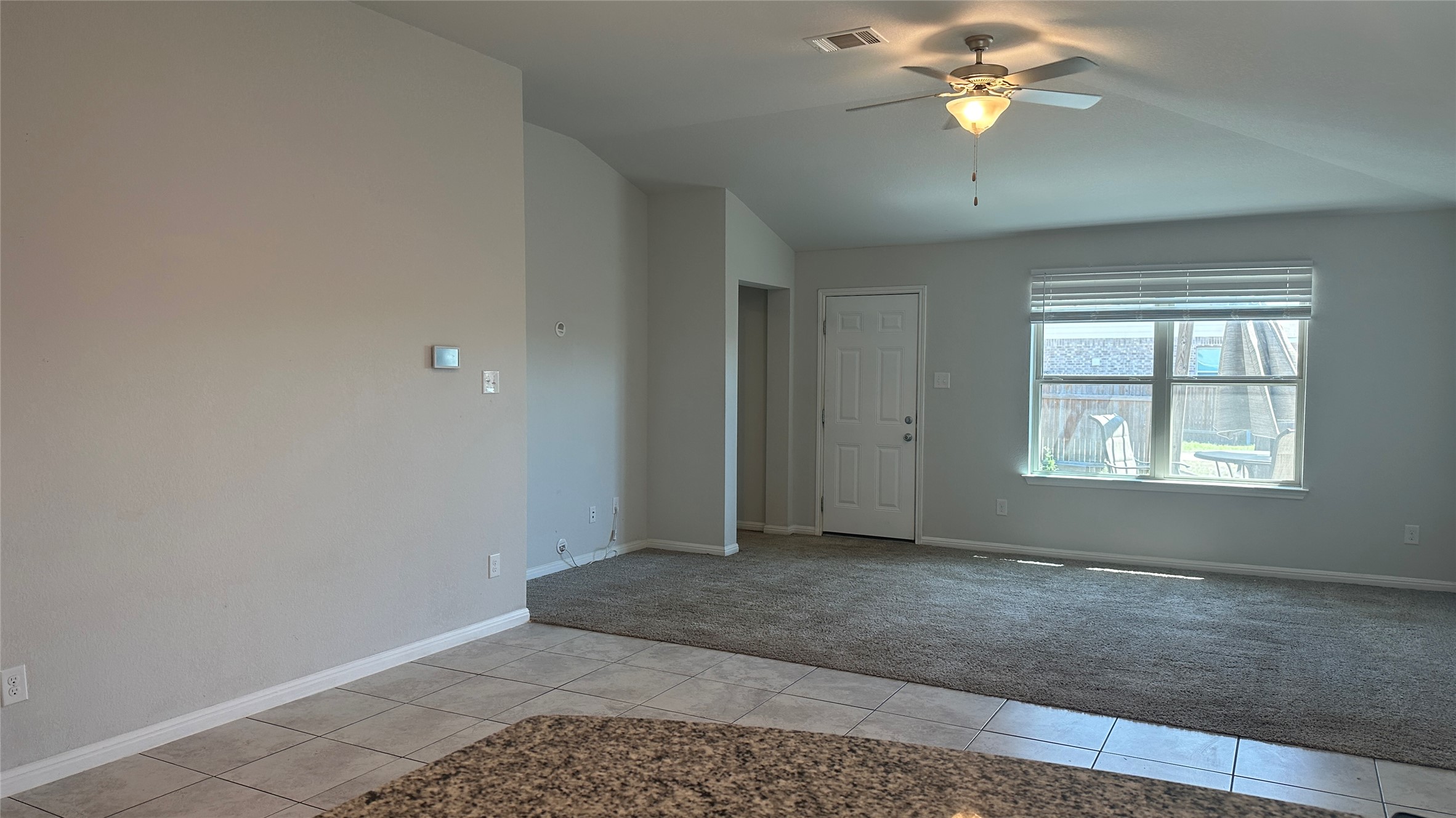 12321 Caldera Way Manor, TX 78653 - Photo 6 of 18 Unfurnished room with light tile patterned floors, ceiling fan, lofted ceiling, and light carpet
