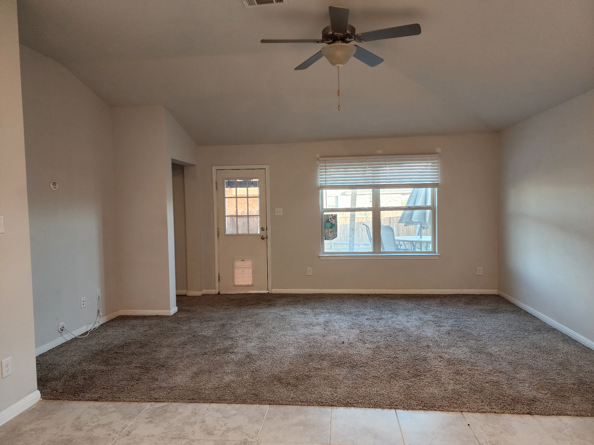 12321 Caldera Way Manor, TX 78653 - Photo 8 of 18 Empty room featuring light colored carpet, ceiling fan, lofted ceiling, and light tile patterned flooring