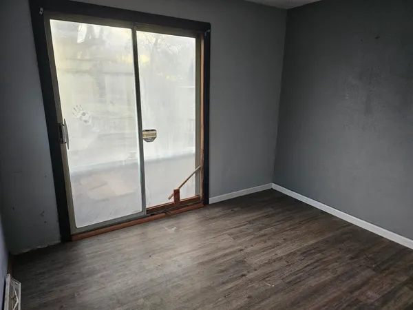 an empty room with wooden floor and door