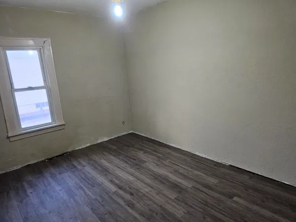 a view of an empty room and wooden floor and window
