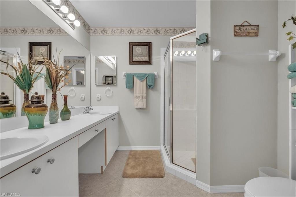 8075 Tiger Cove, Unit 1706 Naples, FL 34113 - Photo 21 of 50 Full bathroom with a shower stall, double vanity, and light tile patterned floors