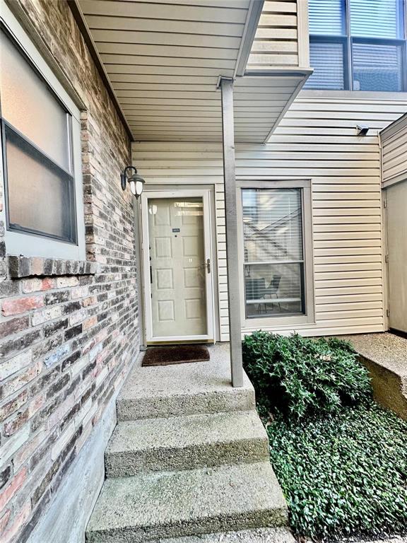 7340 Skillman Street, Unit 405 Dallas, TX 75231 - Photo 14 of 18 Entryway featuring a light-colored paneled door, concrete steps, brick exterior siding, and a covered porch area