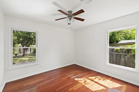 a view of empty room with wooden floor and fan