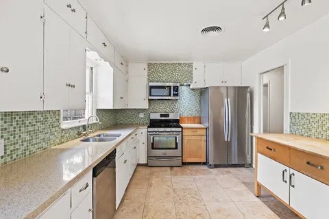 a kitchen with stainless steel appliances a stove a sink a refrigerator and a refrigerator